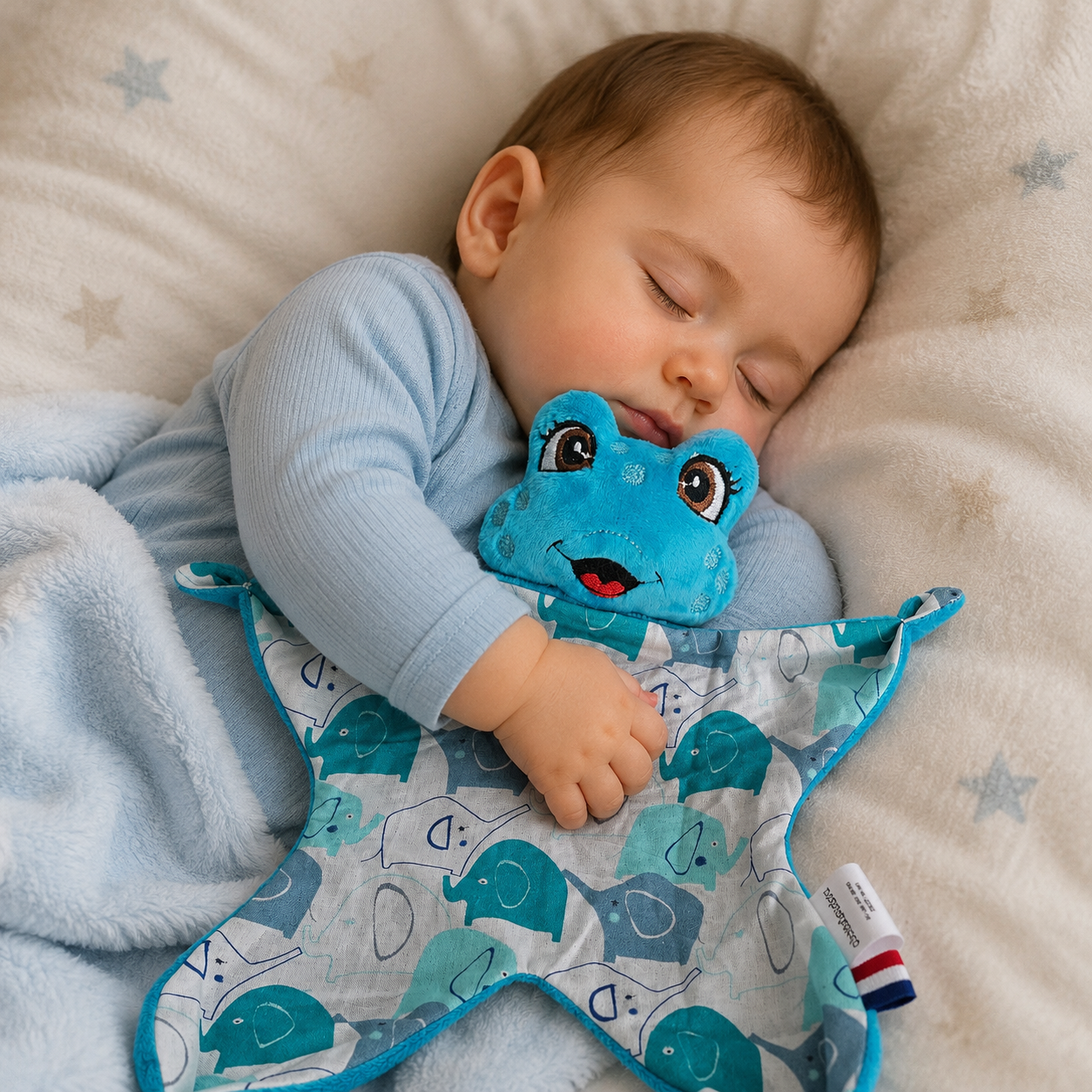 Bébé endormi câlinant un doudou plat grenouille bleue à motif éléphants