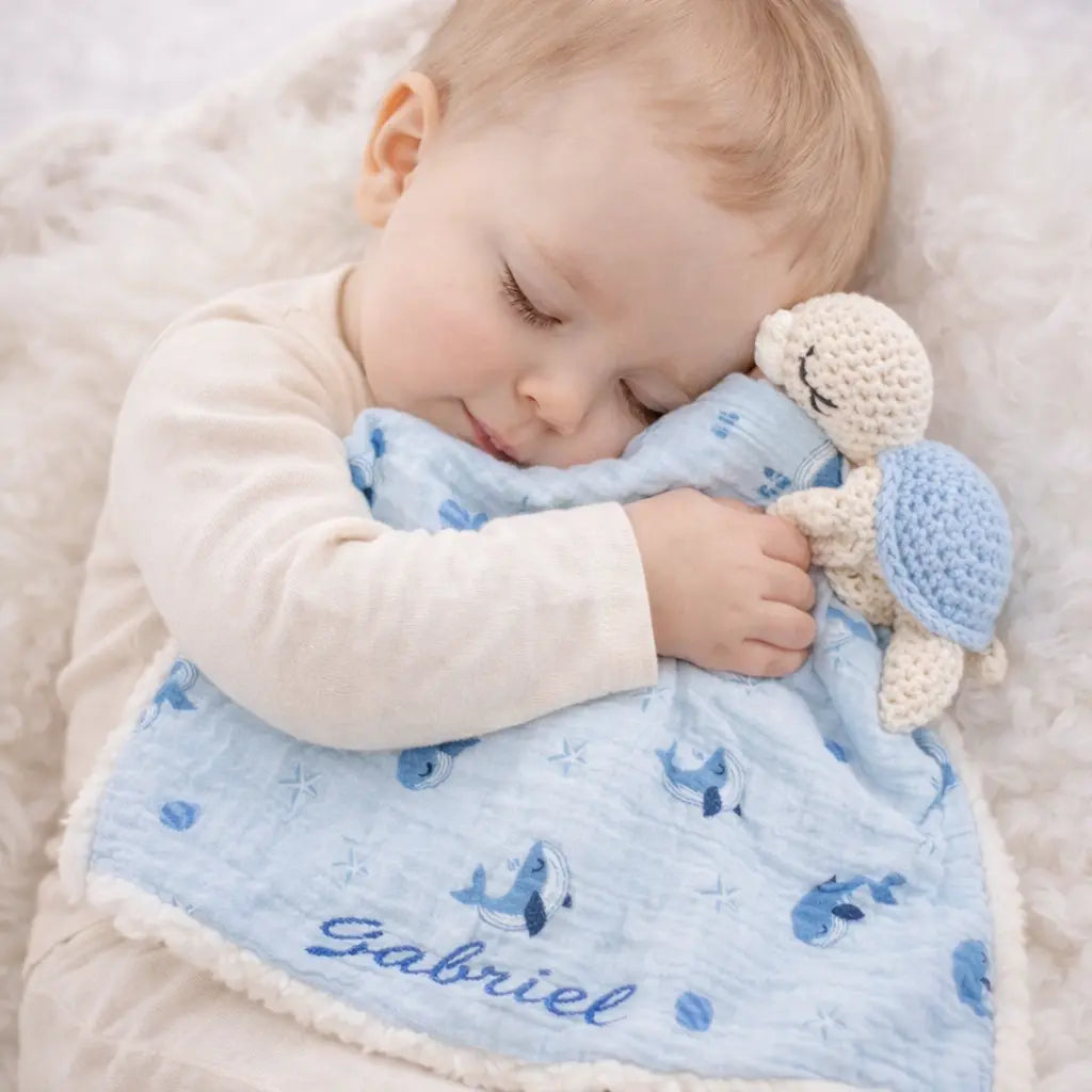 Bébé faisant un câlin à un doudou personnalisé au crochet tortue avec prénom Gabriel