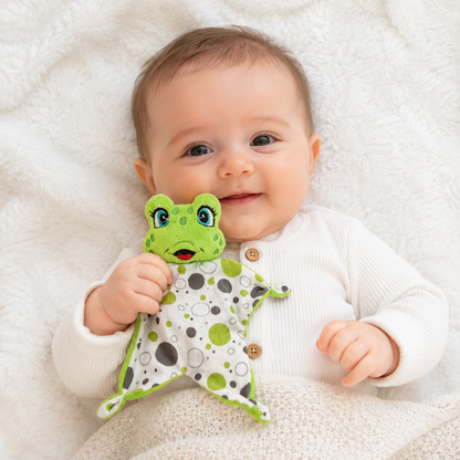 Enfant tenant un mini doudou grenouille 16 cm en peluche avec lange à pois vert et gris