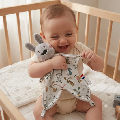 Doudou lapin personnalisé Chtitdoudou tenu par un bébé souriant dans son lit