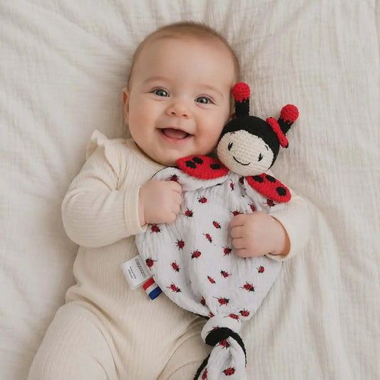 Bébé tenant un doudou bébé personnalisé au crochet en forme de coccinelle, doudou fait main doux pour naissance