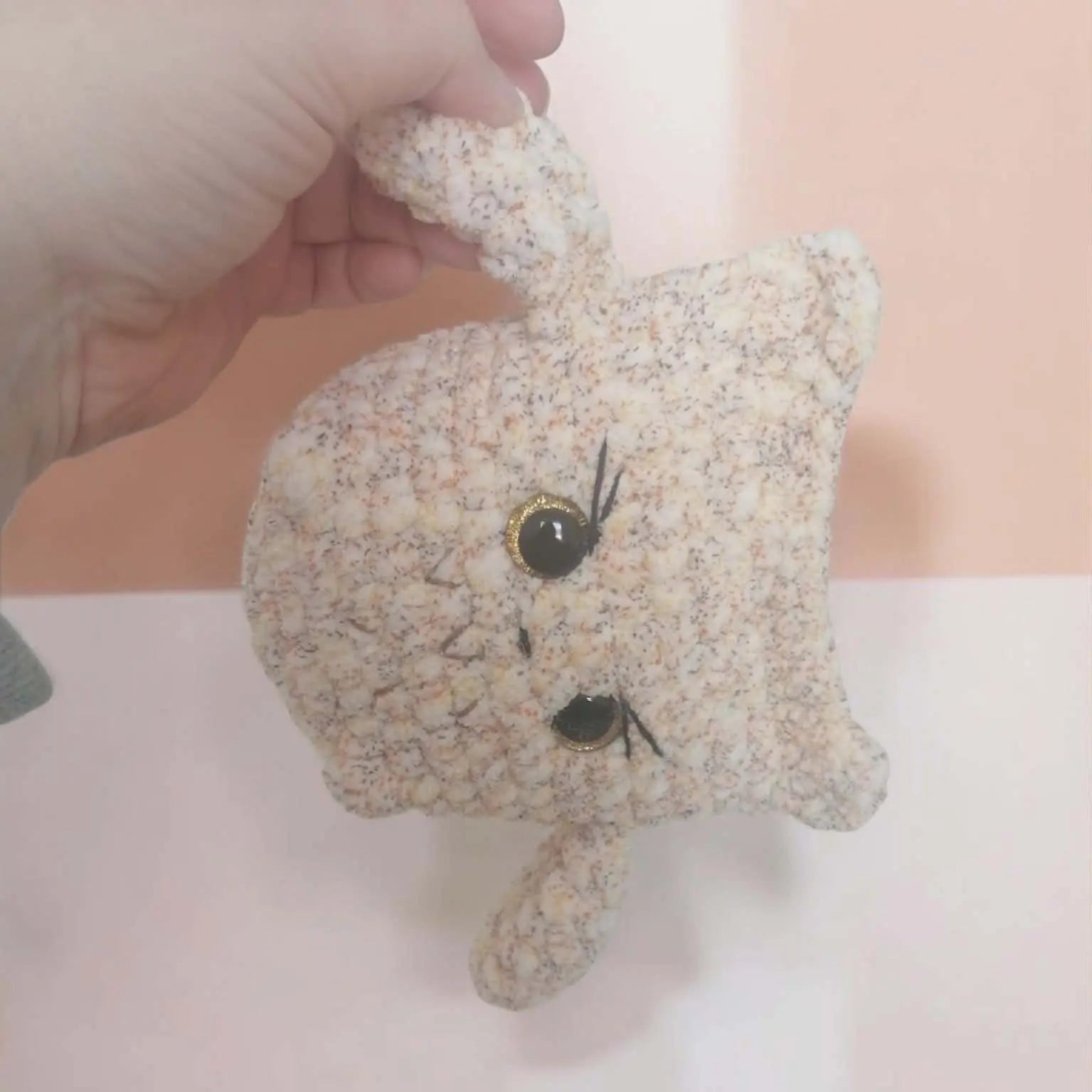 Hibou en crochet fait main avec de grands yeux expressifs, posé sur un fond neutre.