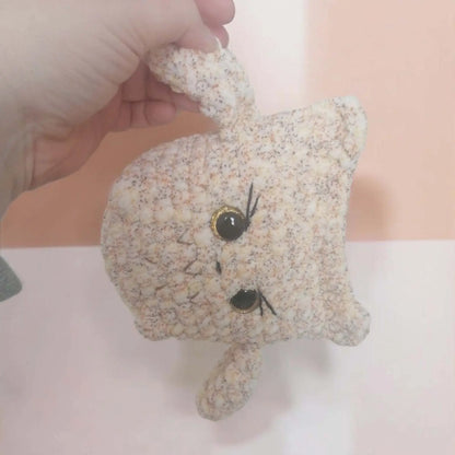 Hibou en crochet fait main avec de grands yeux expressifs, posé sur un fond neutre.